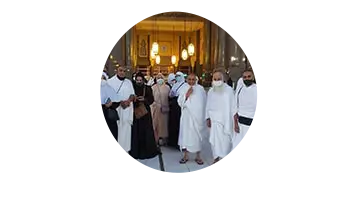 Group photo of Umrah travelers in front of the Kaaba